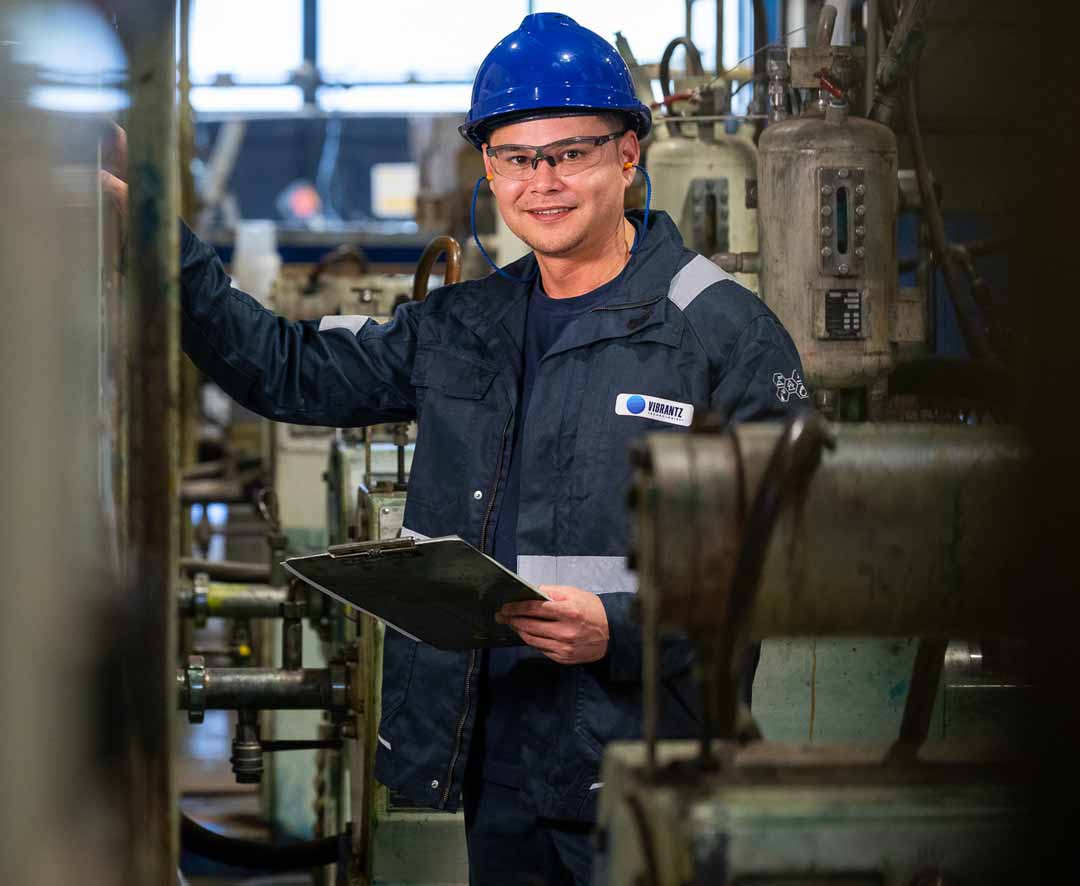 Inspector holding a clipboard wearing safety helment and Vibrantz jacket